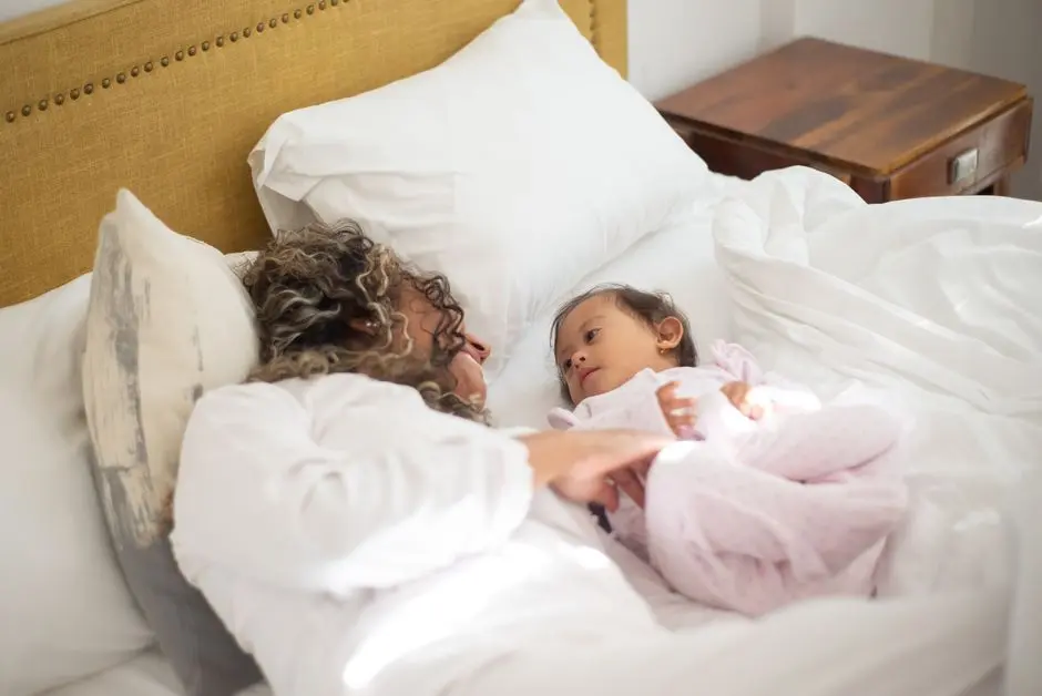 Ibu dan anak tersenyum saat merapikan tempat tidur di pagi hari